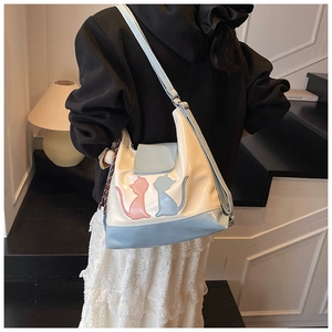 Détail du sac cabas bicolore avec broderie de chat et breloque à pampilles décorative