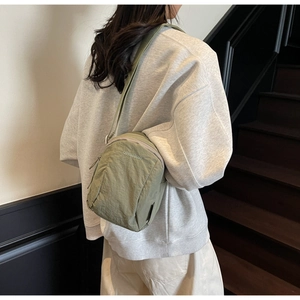 Détail du sac bandoulière en nylon vert avec texture plissée et logo brodé