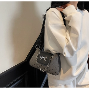 Detail of grey heart pattern fabric and silver bow clasp on stylish underarm bag