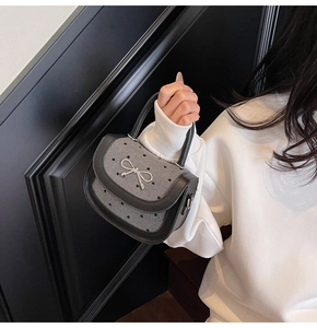 Detail of grey heart print baguette bag with black leather handle and silver bow