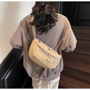 Dettaglio della borsa a tracolla beige a mezzaluna con cerniere e trama in tessuto nylon