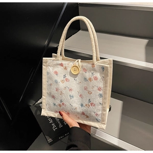 Detailed close-up of floral lace canvas handbag with woven rope handles and wood button