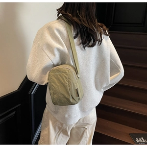 Gros plan du sac bandoulière en nylon vert olive montrant la texture et la sangle