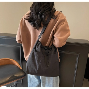 Detailed view of a large black nylon drawstring bucket bag worn by a model in a casual setting