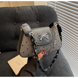 Detail of denim bag with heart prints, leather flap, silver bow and floral chain strap