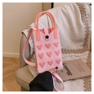 Detailed view of pink knitted mini bag featuring 3D hearts and matching handle strap