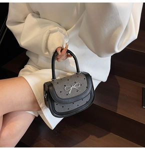 Detail of grey heart-patterned baguette bag with silver bow and black leather trim