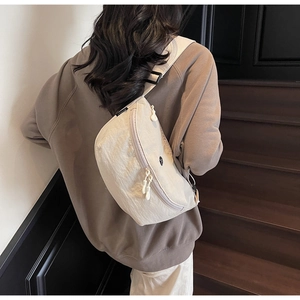 Dettaglio della borsa a tracolla minimalista in nylon beige con doppia cerniera e cinghia
