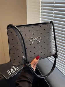 Chic grey canvas shoulder bag with black heart prints and a silver metal bow accent