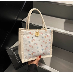 Detailed close-up of cream canvas tote bag with floral lace overlay and large wooden button