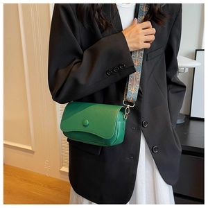 Detail of green pebble leather crossbody bag with a vintage pattern wide shoulder strap