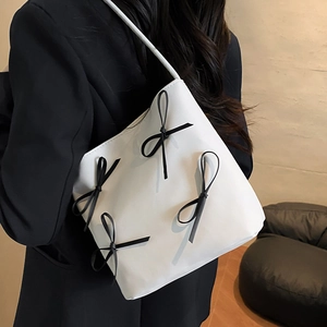 Minimalist white PU leather shoulder bag with chic black bows shown on model
