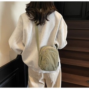 Petit sac bandoulière en nylon vert olive avec sangle réglable porté par un modèle