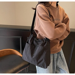 Detail view of black nylon drawstring bucket bag with large pockets and adjustable strap