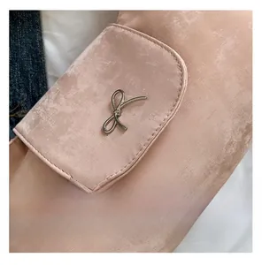 Détail du sac en tissu rose clair avec nœud en métal argenté et texture mate
