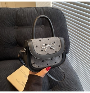 Detail of silver bow metal buckle on a grey polka dot fabric baguette bag with leather strap