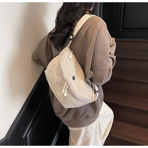 Dettaglio della borsa a mezzaluna in nylon crema con zip e finitura in tessuto testurizzato