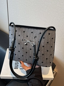Chic grey knitted shoulder bag featuring black polka dots and a silver bow clasp detail