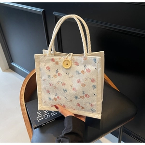 Detail of floral lace handbag featuring a large wooden button and braided rope handle