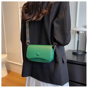 Model wearing a vibrant green textured leather crossbody bag with ethnic pattern strap