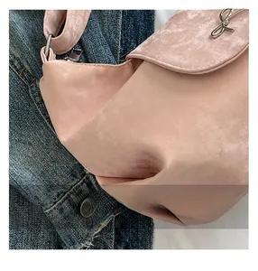 Gros plan sur le sac rose mat avec breloque nœud argenté sur fond en jean bleu