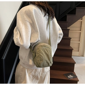 Détail de la mini sacoche en nylon vert montrant la bandoulière réglable et le logo imprimé