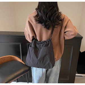 Detailed back view of model wearing a black drawstring bucket bag with large front pockets