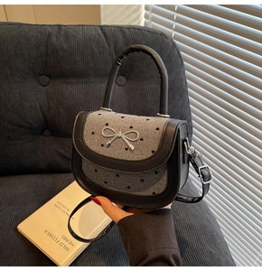 Detail of mini saddle bag with silver bow hardware and heart-patterned tweed material
