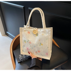 Detailed close-up of white lace tote bag with colorful floral prints and wooden button