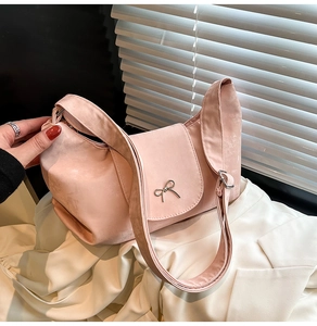 Gros plan détaillé du sac hobo en daim rose avec un élégant nœud en métal argenté