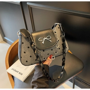 Detail of polka dot fabric, silver bow buckle, and floral chain on the shoulder bag