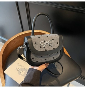 Close-up of wool baguette bag with polka dots, leather trim and silver bow detail