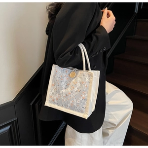 Detail view of floral lace tote bag with rustic hemp handles and large wooden button closure