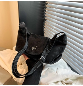 Détail d'un sac bandoulière en velours noir avec nœud argenté et large sangle réglable