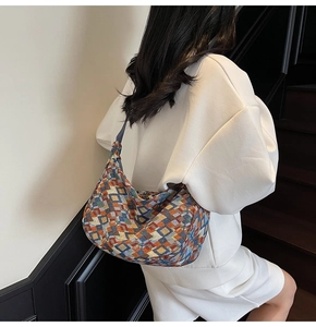 Detail of colorful geometric pattern hobo bag worn by a model on a minimalist staircase
