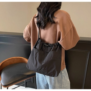 Detailed back view of a large black nylon drawstring bucket bag on a fashion model