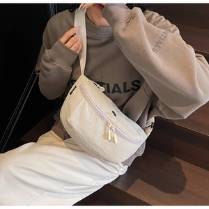 Dettaglio di una borsa a tracolla a mezzaluna beige con trama in nylon e cinturino