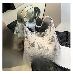 Dettaglio di una borsa tote bianca con stampe vintage di farfalle grigie e stelline