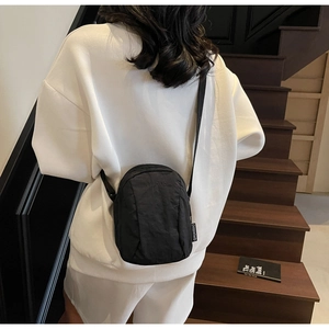 Détail d'un mini sac à bandoulière en nylon noir léger avec logo de marque en relief