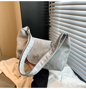 Détail du sac à bandoulière en daim gris argenté avec nœud métallique et rabat chic