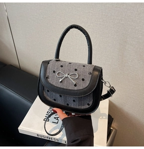 Detailed shot of grey polka dot saddle bag with silver bow accent and leather trim