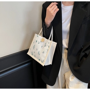 Close-up of floral lace canvas tote bag with wooden button and braided handles