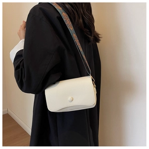 Detail of the white lychee grain leather crossbody bag with ethnic embroidered strap