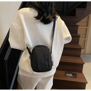 Vue arrière d'un mannequin portant le mini sac bandoulière en nylon noir avec sangle