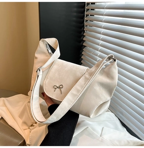 Détail du sac à bandoulière en velours crème avec boucle nœud argenté et texture mate douce