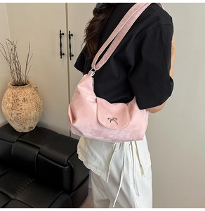 Détail d'un sac hobo rose avec un nœud métallique argenté et une texture en daim mat doux