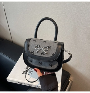 Close-up of a chic grey knit baguette bag with black bow print and silver metal buckle