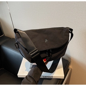 Dettaglio della borsa a tracolla in nylon nero con tracolla regolabile e logo circolare