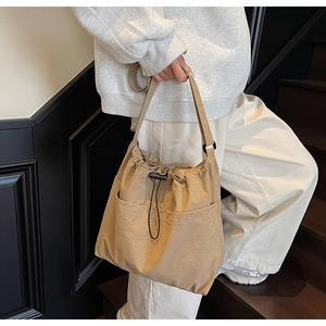 Detail view of the khaki nylon drawstring bucket bag with buckle and front pocket