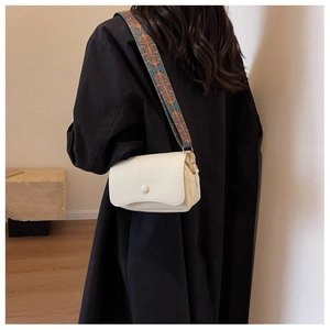 Detail view of cream lychee texture leather crossbody bag with ethnic wide strap